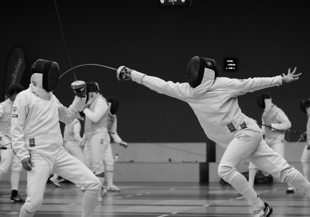 a group of people on a court with fencing equipment