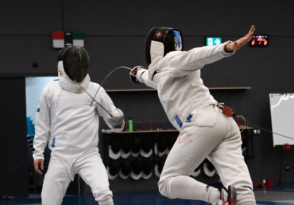 a man in white fencing gear jumping in the air