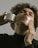 Close-up of a person applying hair system tape on scalp in a bright room.