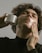 Close-up of a person applying hair system tape on scalp in a bright room.