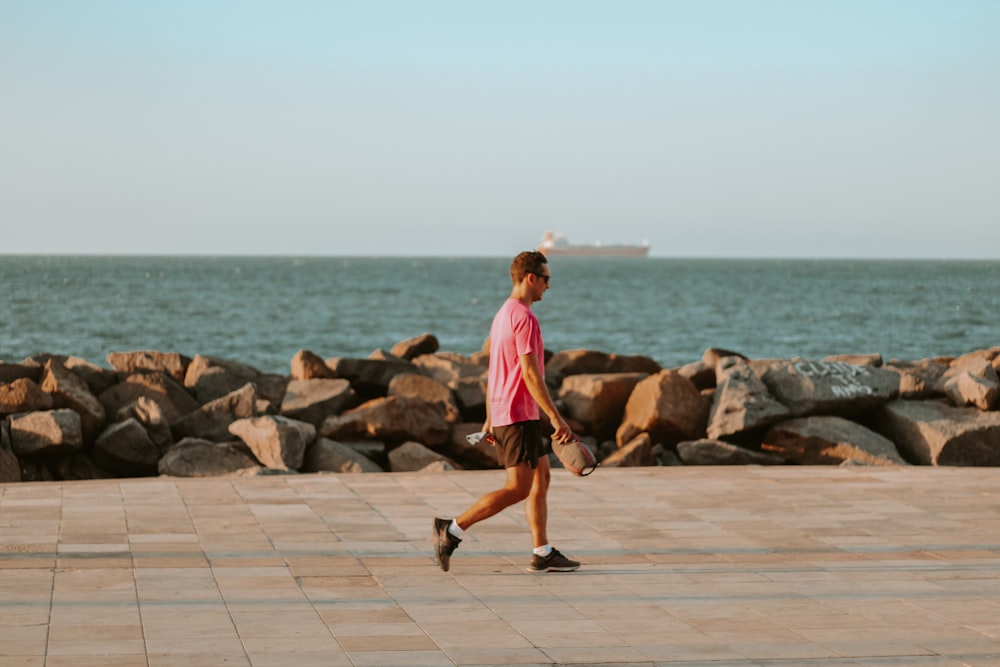 a man walking on a sidewalk next to a body of water