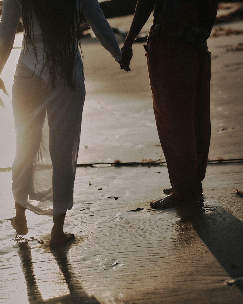 um homem e uma mulher de mãos dadas na praia