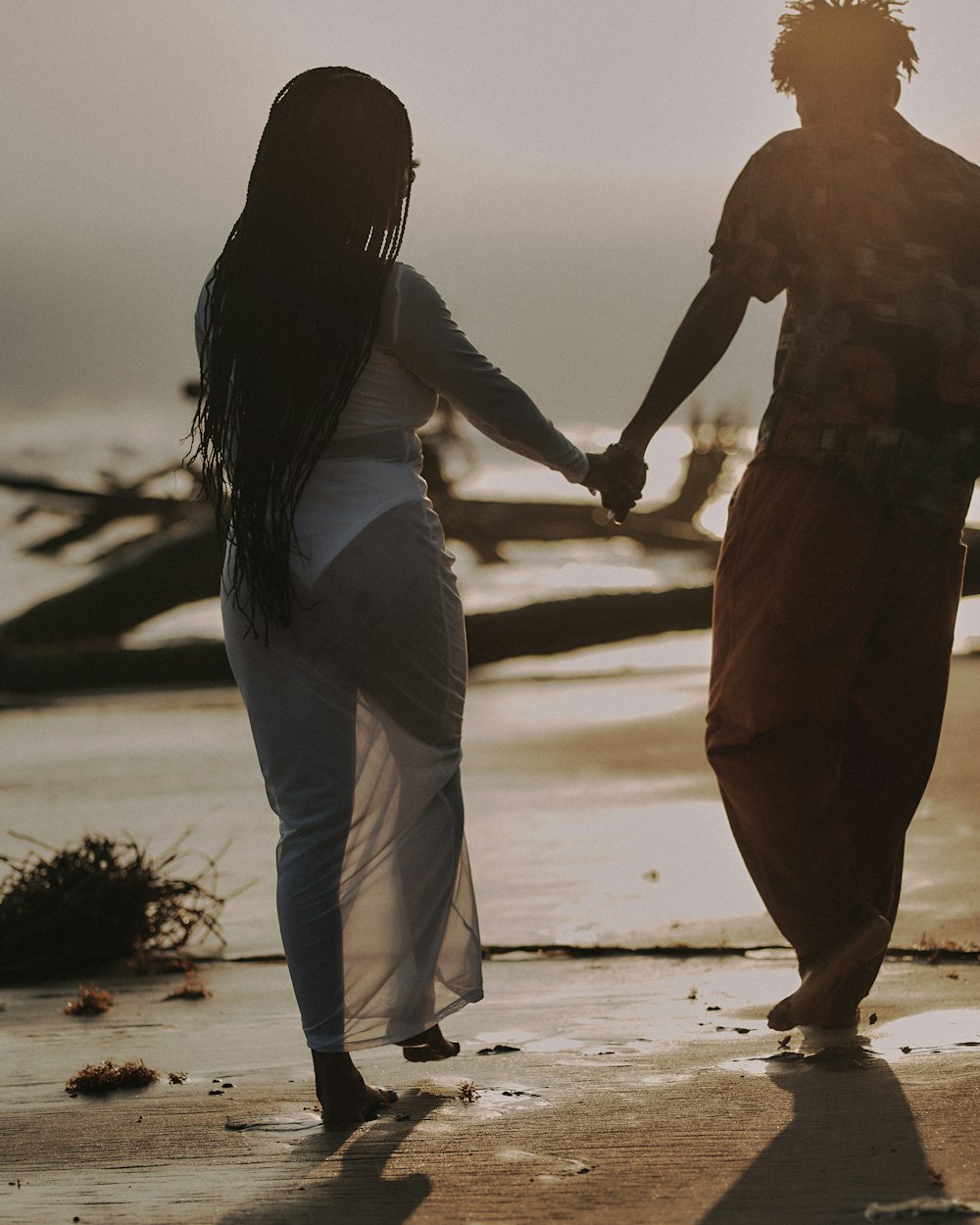 a man and a woman holding hands on the beach