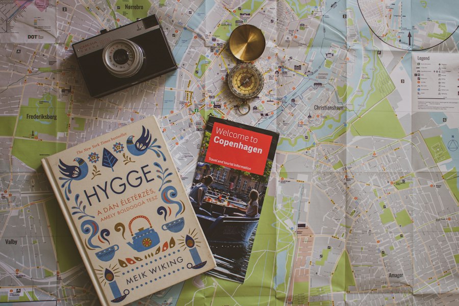 Travel brochure, map, compass and camera on a table