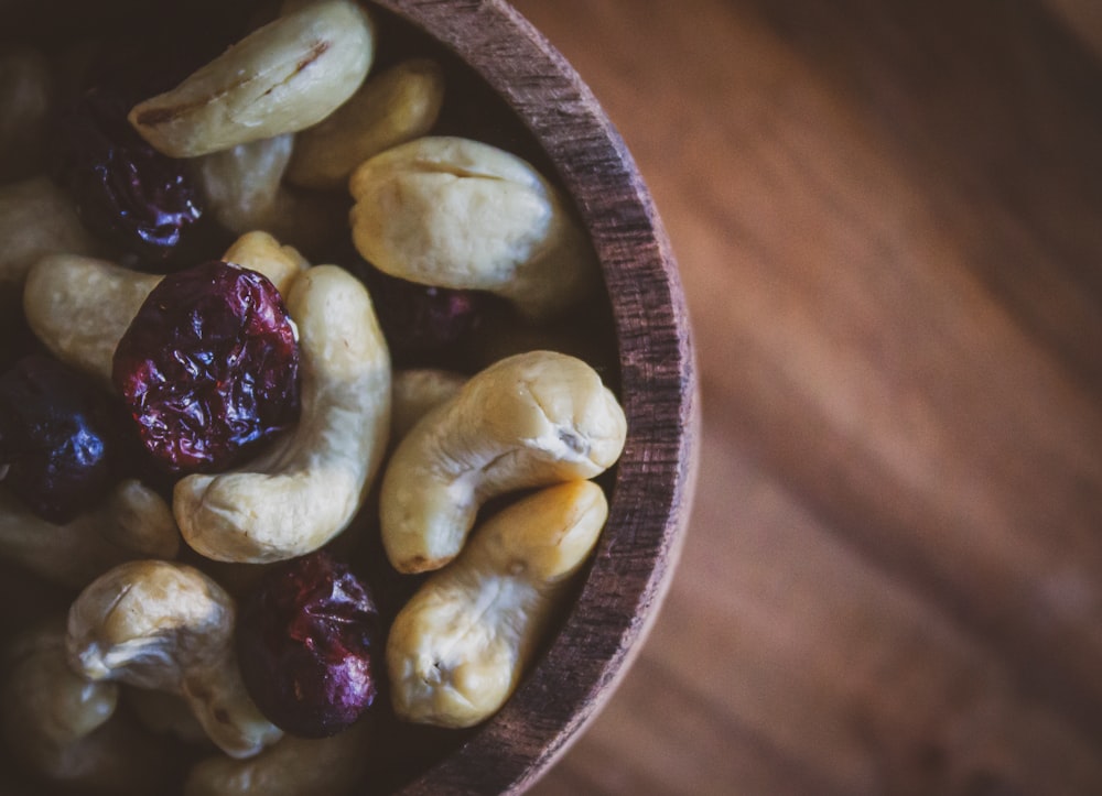 a wooden bowl filled with nuts and dried cranberries