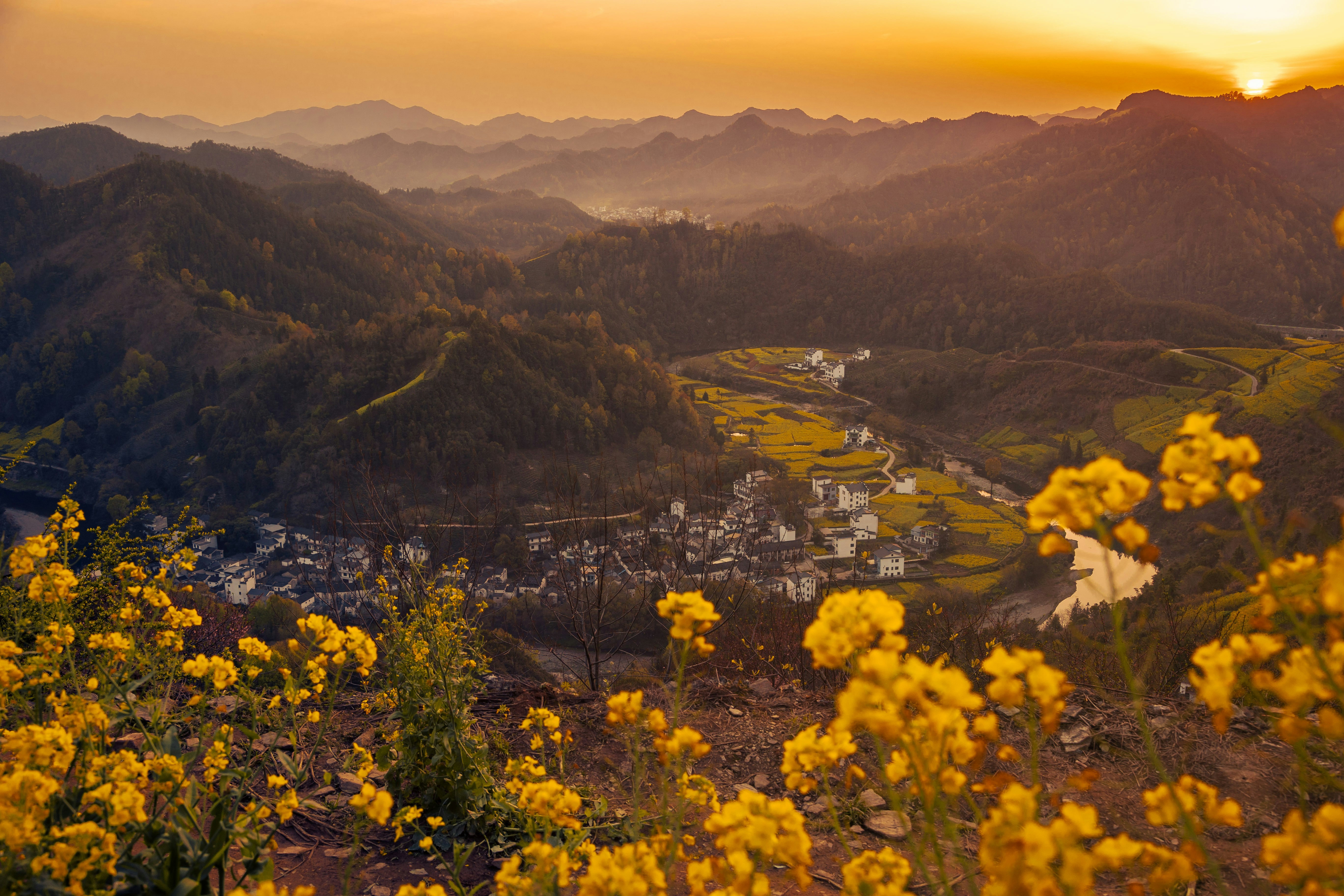 the sun is setting over a village in the mountains