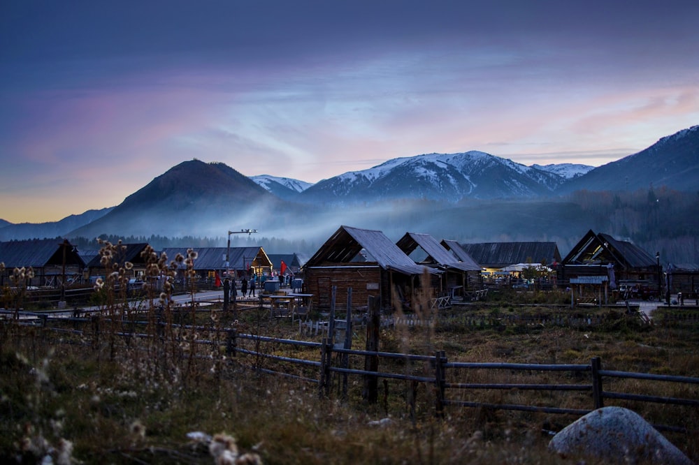 a group of houses in a field with mountains in the background