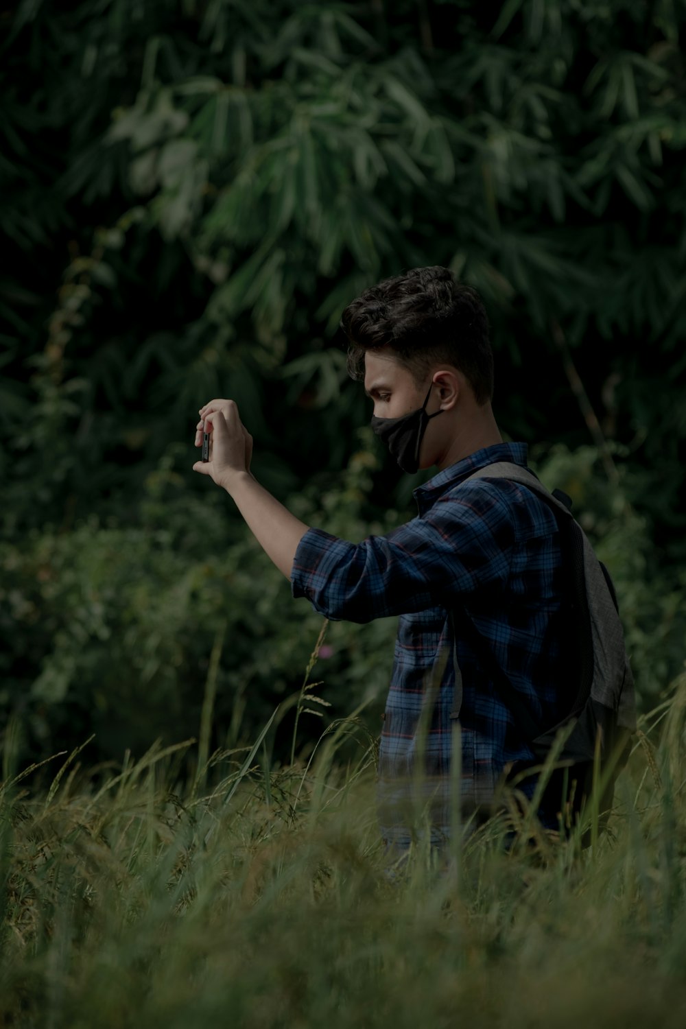 Un homme portant un masque facial prenant une photo avec son téléphone portable