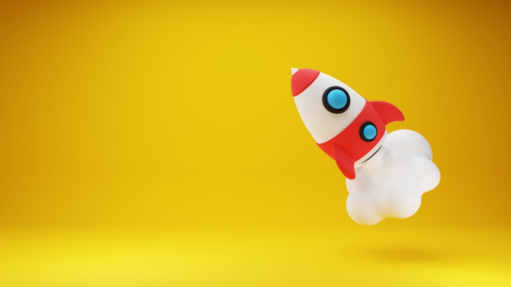 a red and white toy rocket on a yellow background