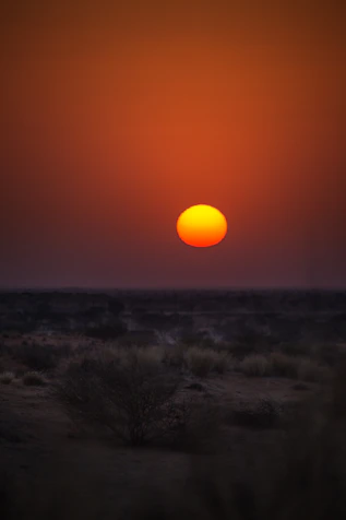 the sun is setting over a desert plain