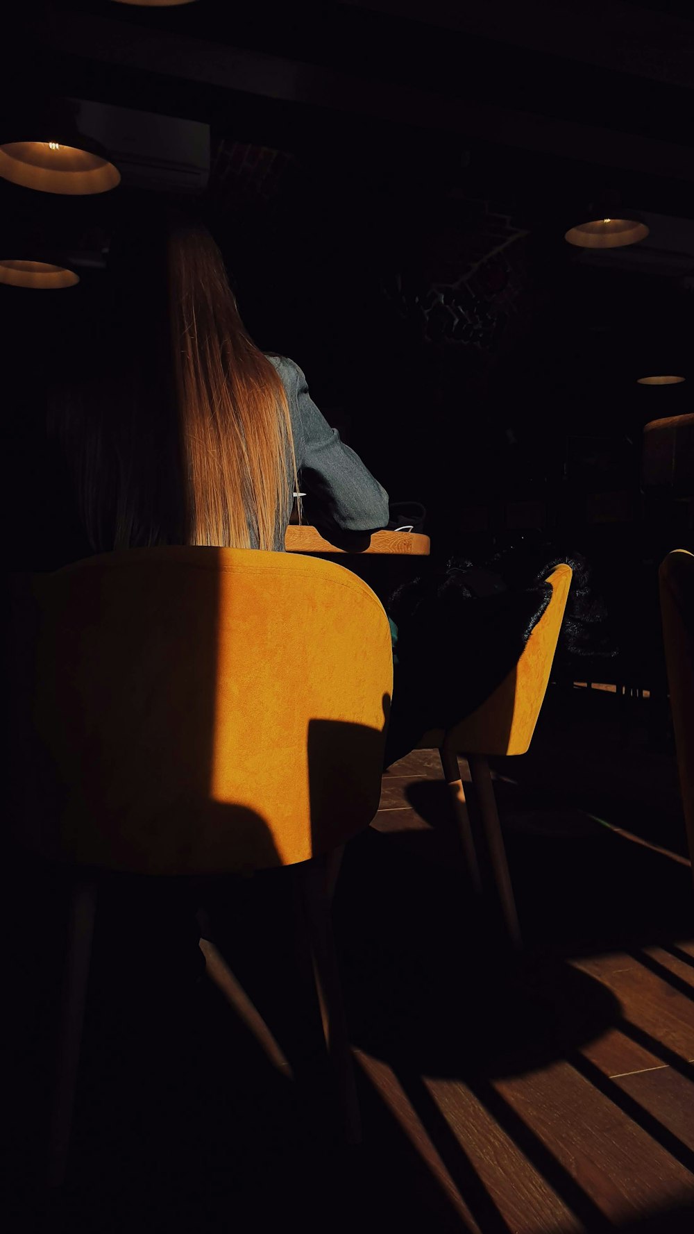 a woman sitting in a yellow chair in a dark room