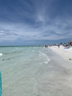 A pristine beach with turquoise water and people enjoying a sunny day under parasols