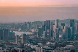 a view of a city with a lake and mountains in the background