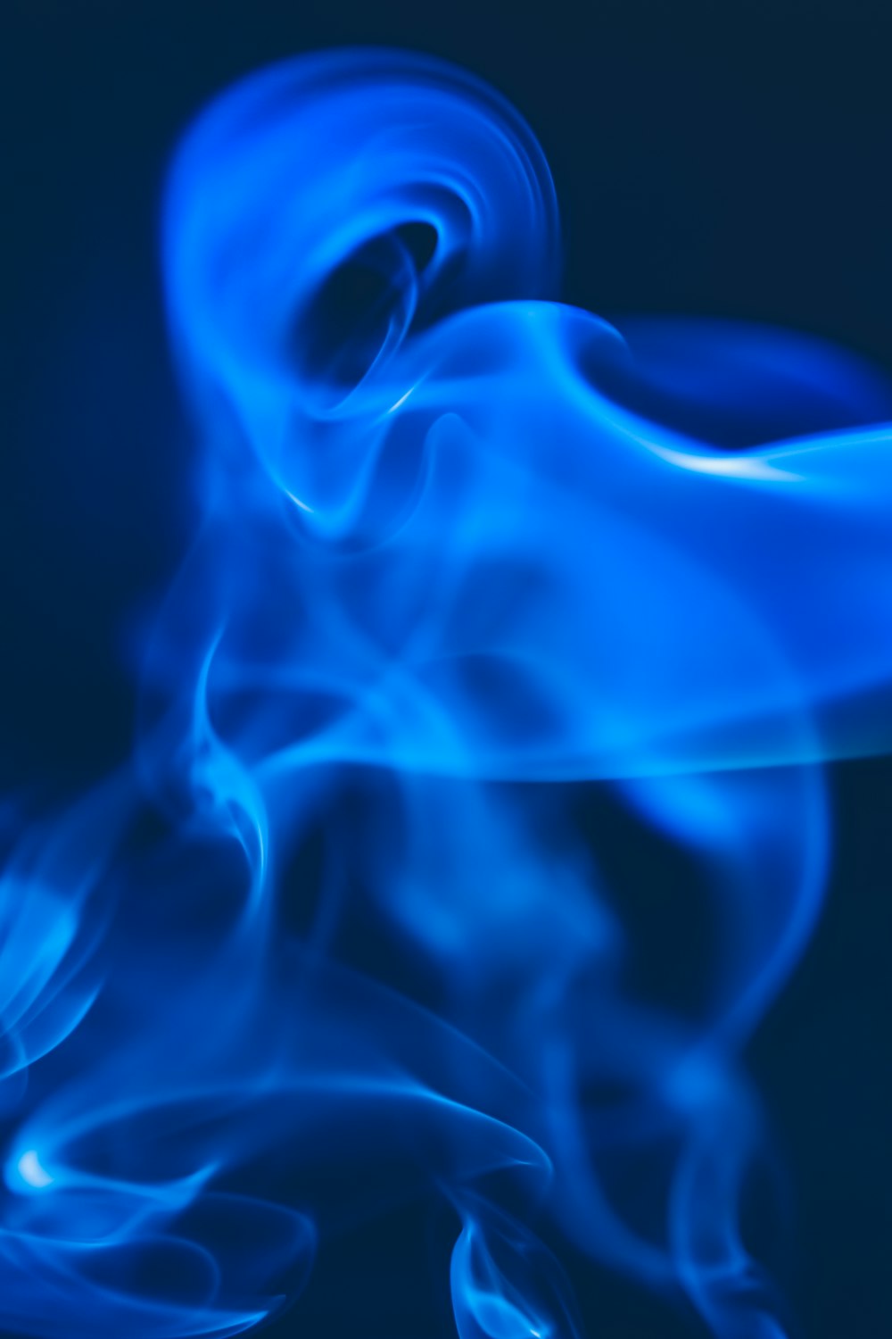 a blue smoke swirls across a black background