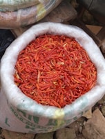 A rustic sack spilling vibrant red chili peppers onto a wooden surface.