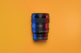 A sleek black and yellow film camera lens close-up, reflecting light.