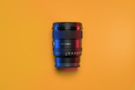 Close-up of a camera lens reflecting dramatic yellow and black tones in a sleek setup.