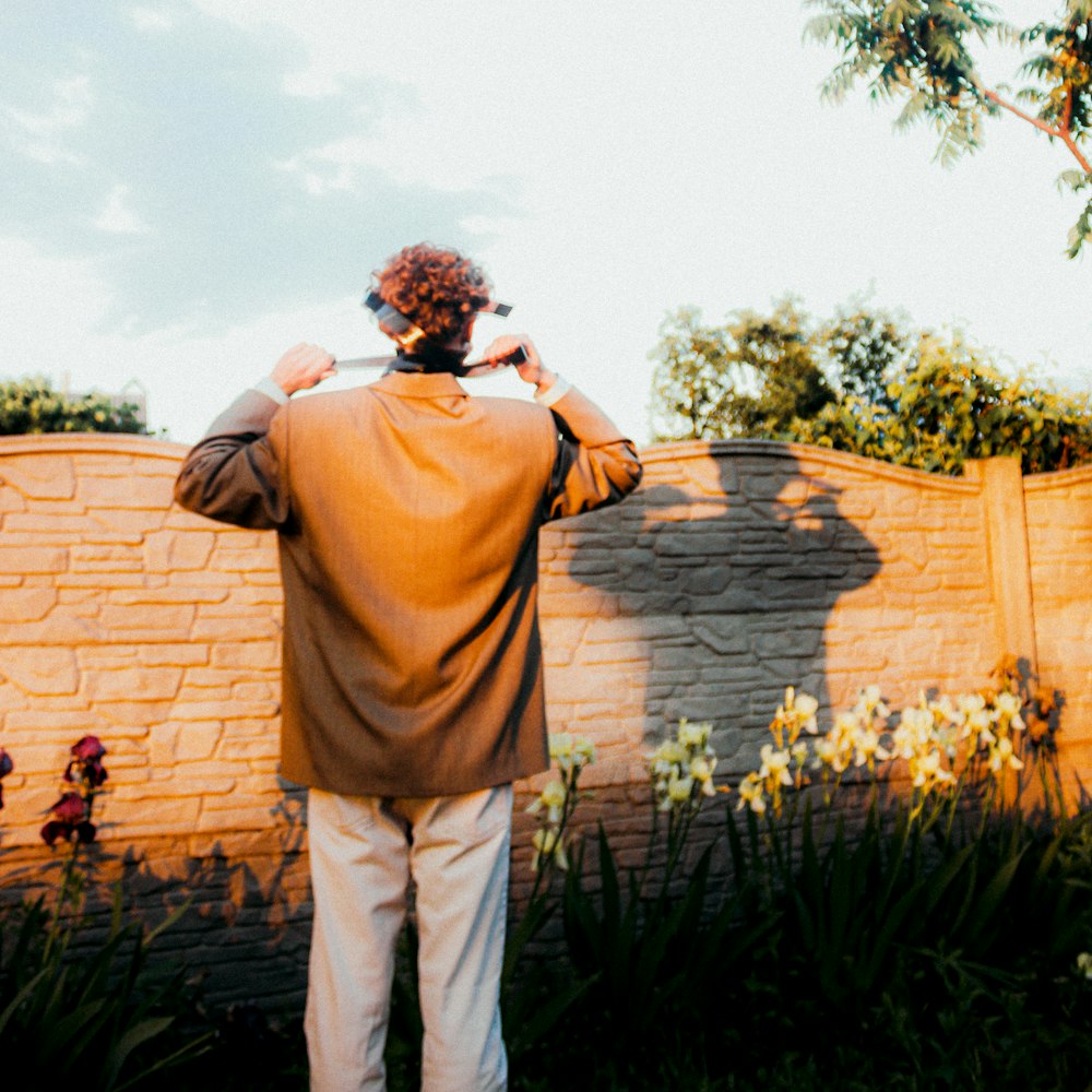 a man standing in front of a brick wall