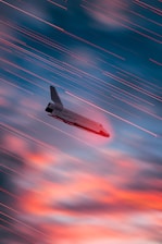 an airplane is flying in the sky at sunset