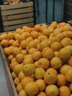 A variety of citrus fruits stacked in a wooden crate.