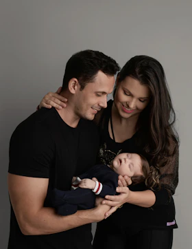 a man and woman holding a baby in their arms