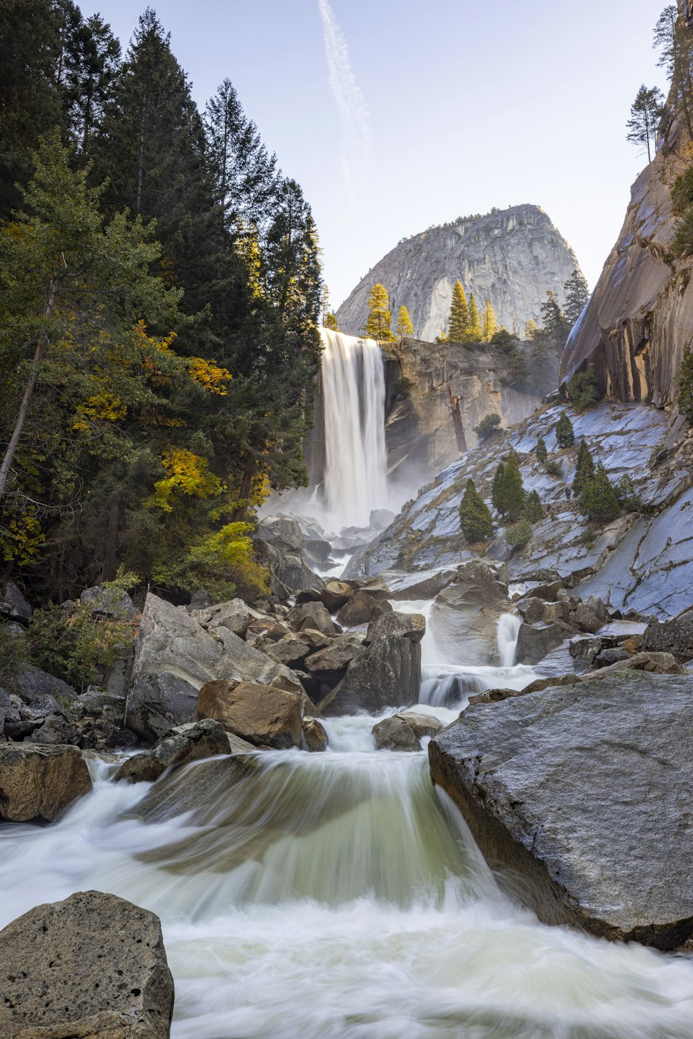 a waterfall with water running down it surrounded by rocks and trees