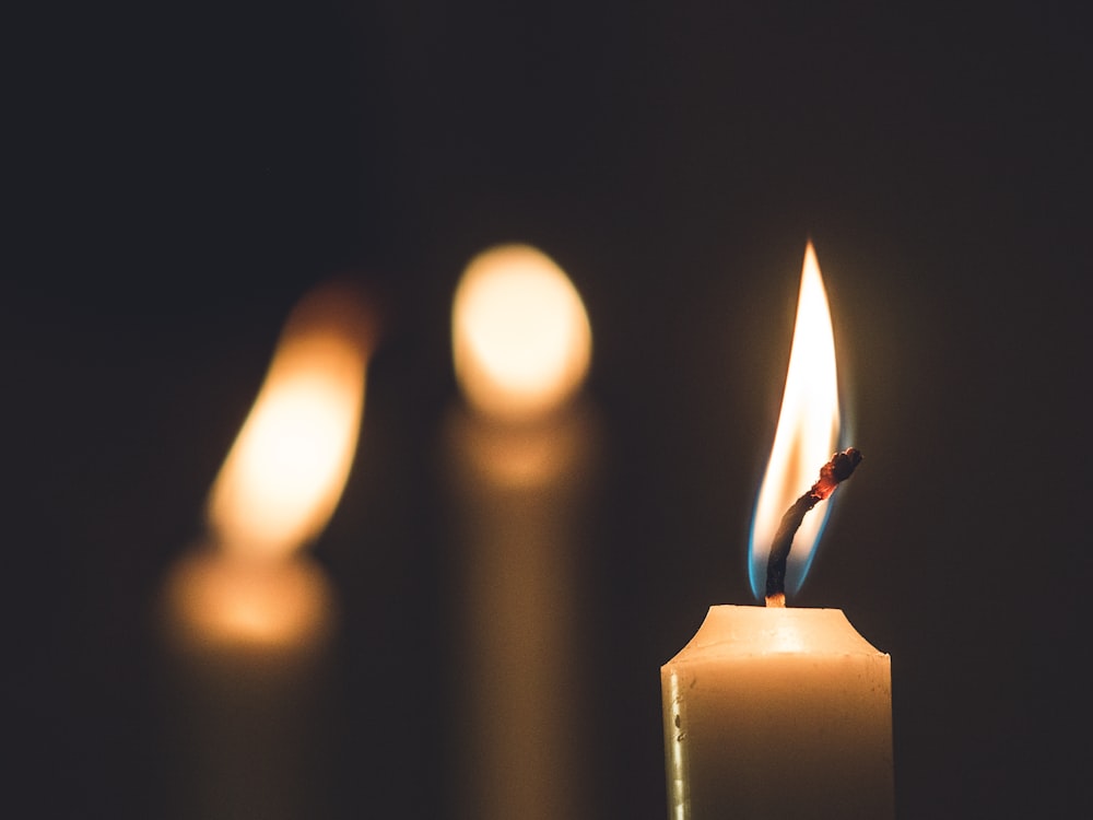 Una candela accesa al centro di una fila di candele accese foto – Candela  Immagine gratuita su Unsplash
