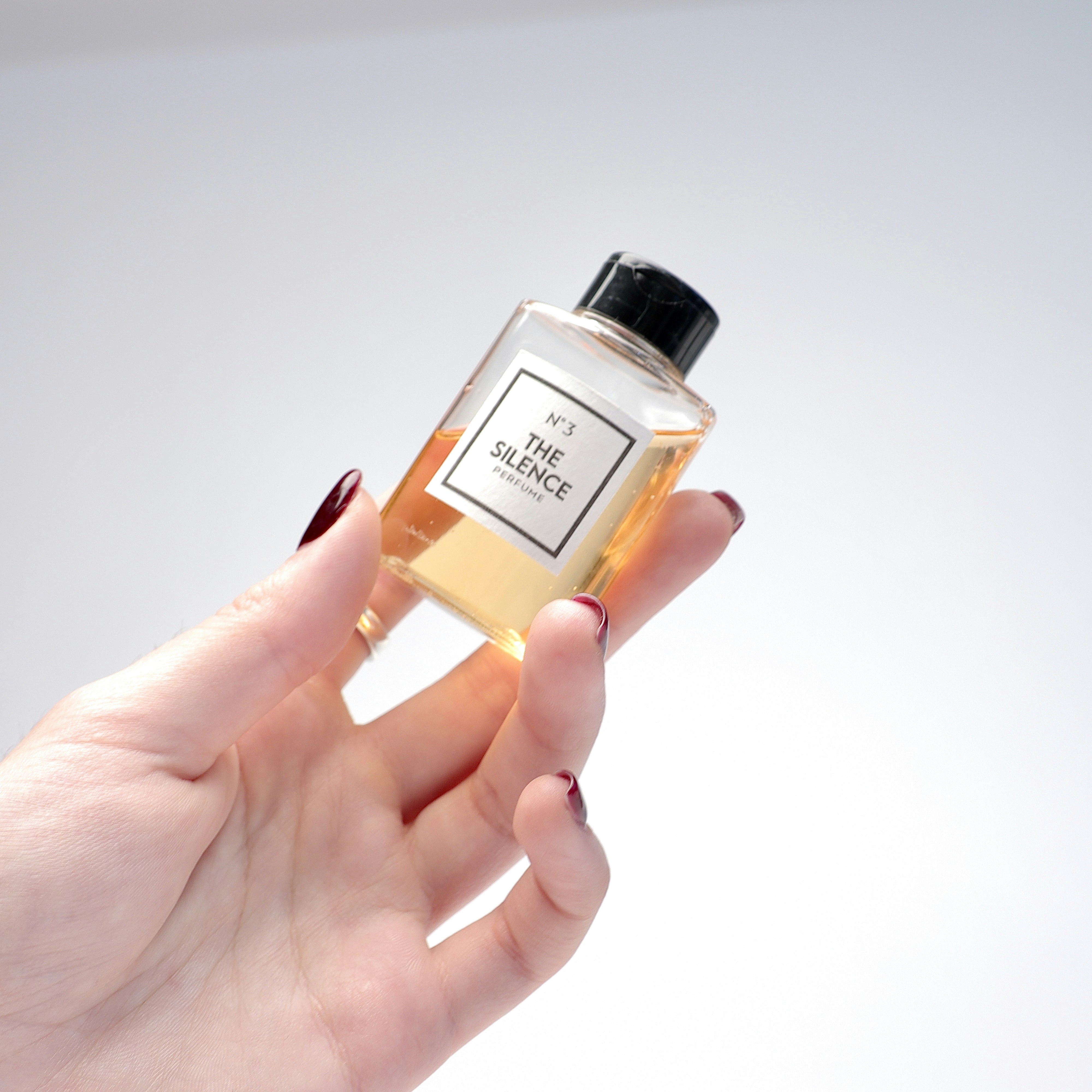 Close up of amber perfume attar in small glass vial, dark background