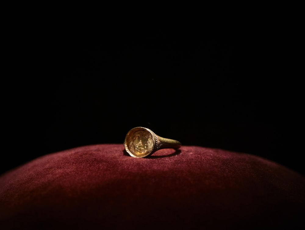 um anel de ouro sentado em cima de uma almofada vermelha