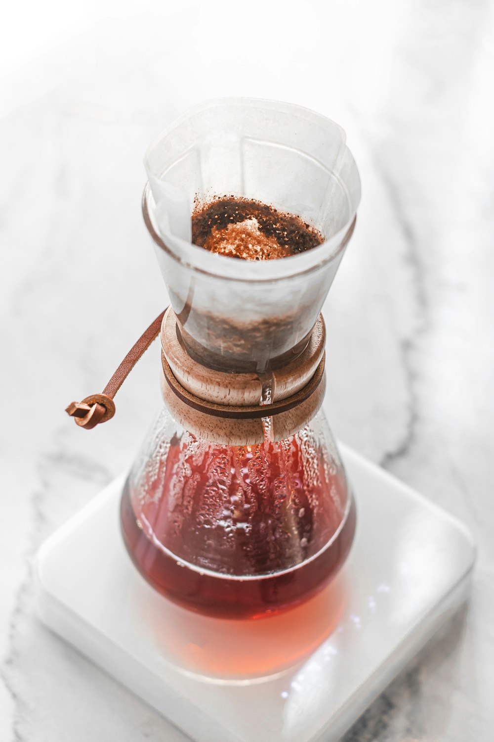 a coffee pot filled with liquid on top of a white plate