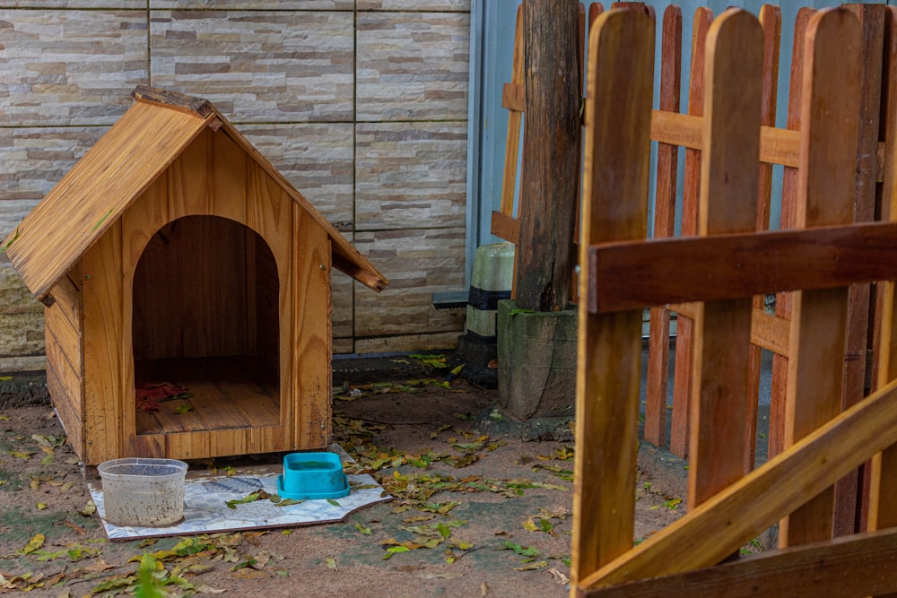 uma casa de cachorro de madeira com um balde de água ao lado dela