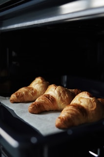 A close-up of golden-brown croissants fresh from the oven.