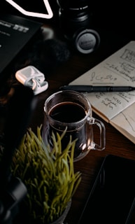 A cozy workspace with a laptop, notebook, and a steaming cup of coffee on a wooden desk.