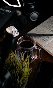 A cozy workspace with a laptop, notebook, and a steaming cup of coffee on a wooden desk.