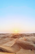 Golden desert dunes under a vast blue sky in Rajasthan at sunset.