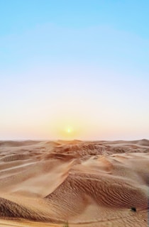 Golden dunes of the Gobi Desert under a vast blue sky at sunset
