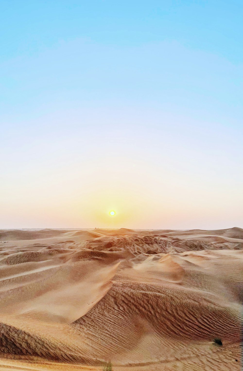 the sun is setting over a desert landscape