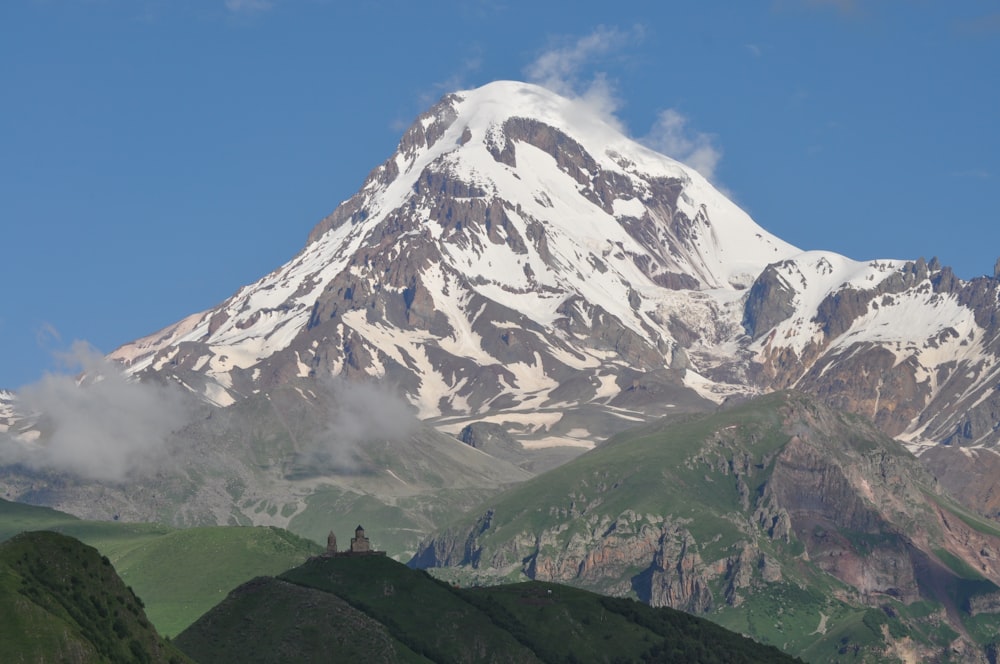 a large snow covered mountain towering over a valley