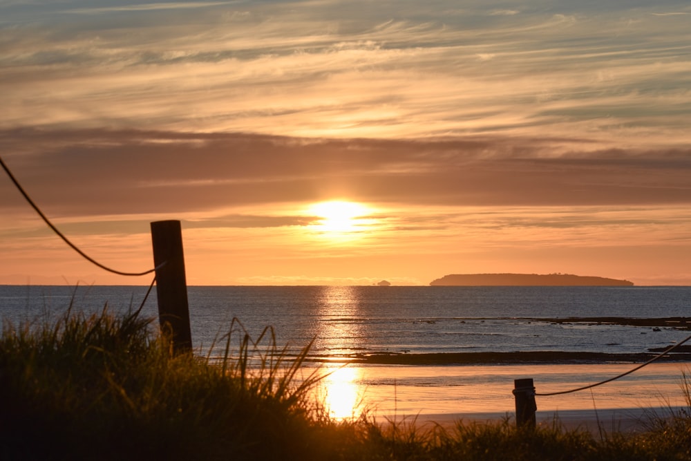 the sun is setting over the ocean on the beach