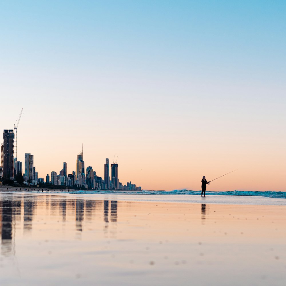 a man standing on top of a beach next to the ocean