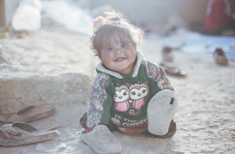 a little girl sitting on the ground with a stuffed animal