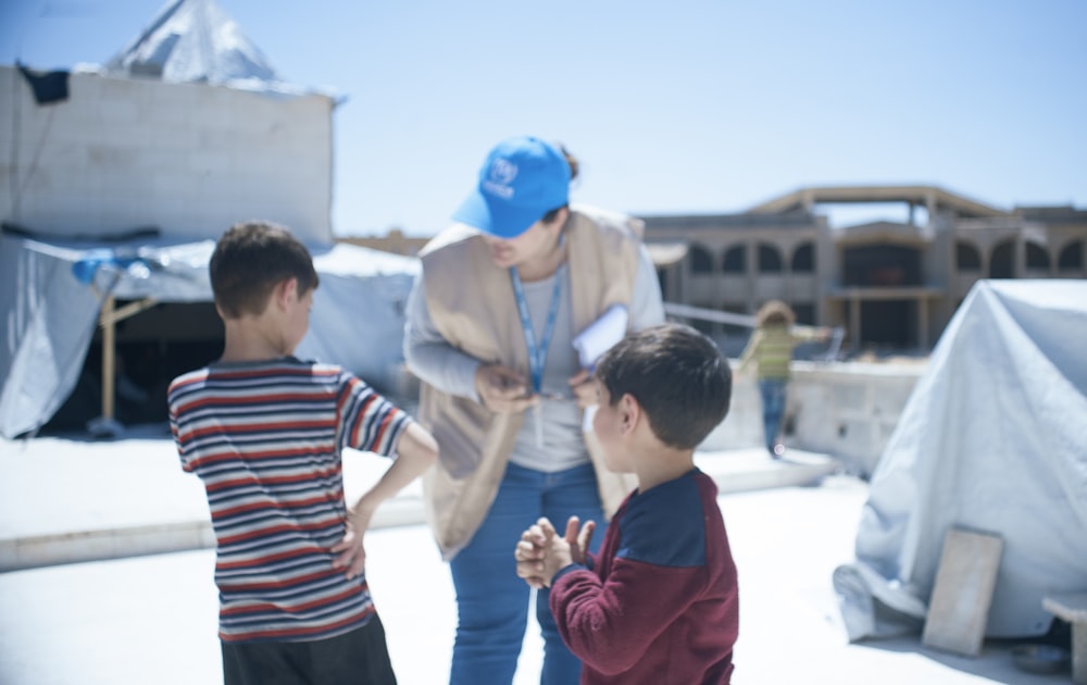 a woman standing next to two small boys