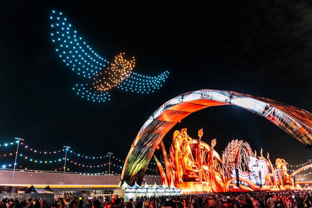 Una multitud de personas de pie alrededor de un carnaval por la noche