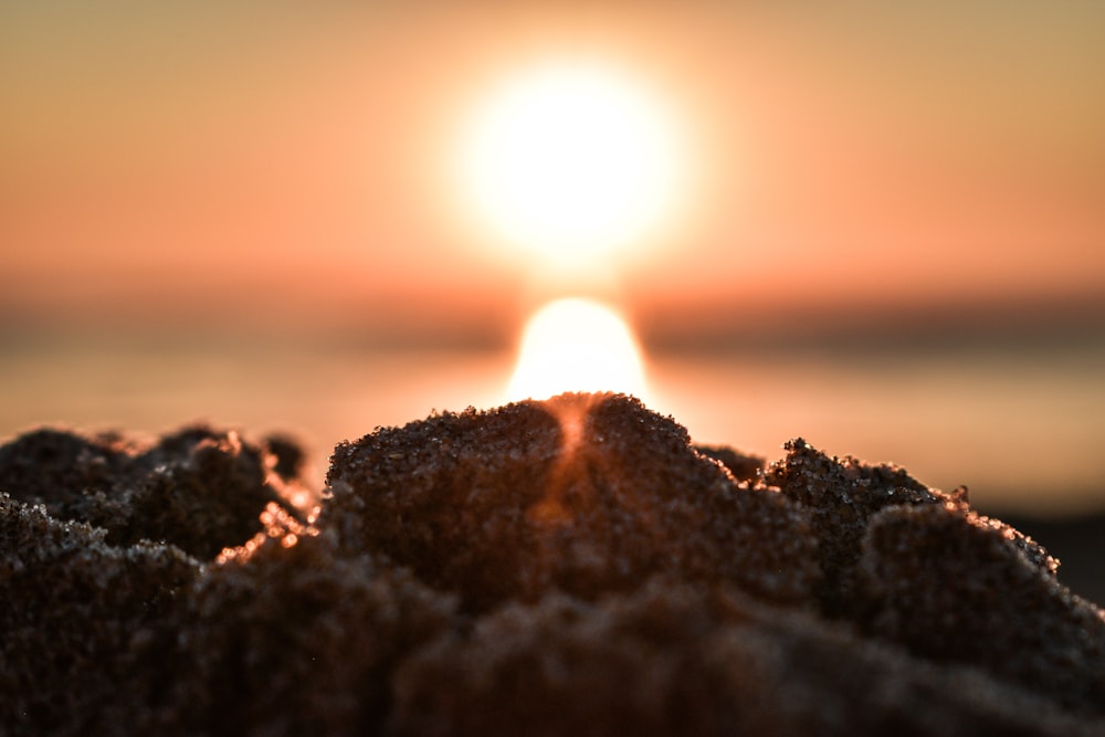 the sun is setting over a beach with sand