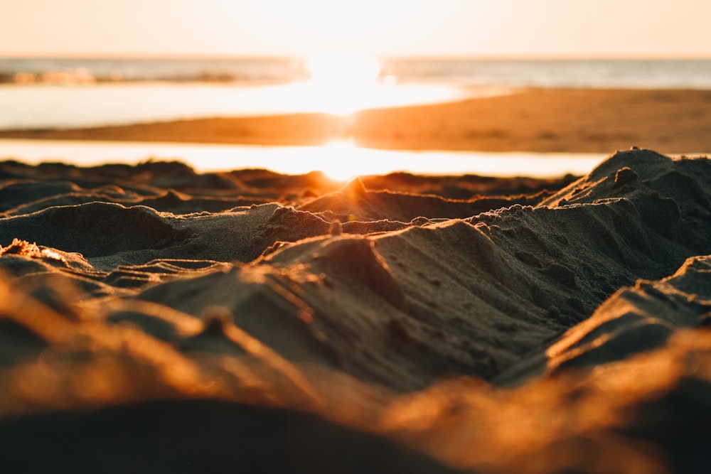 the sun is setting on a sandy beach