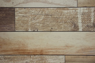 Several rectangular wooden planks arranged horizontally, each displaying a unique grain pattern and varying shades of brown with visible textures.