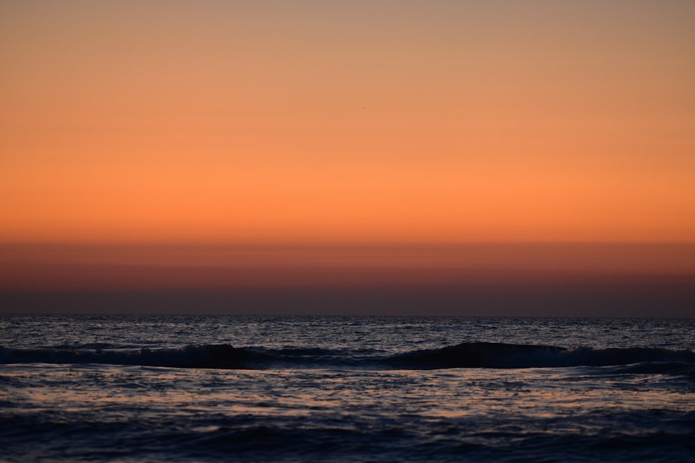 a sunset over a body of water with waves