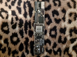 Close-up of a MacBook motherboard being diagnosed with specialized tools.