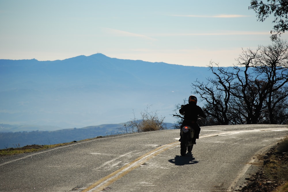 a man riding a motorcycle down a curvy road