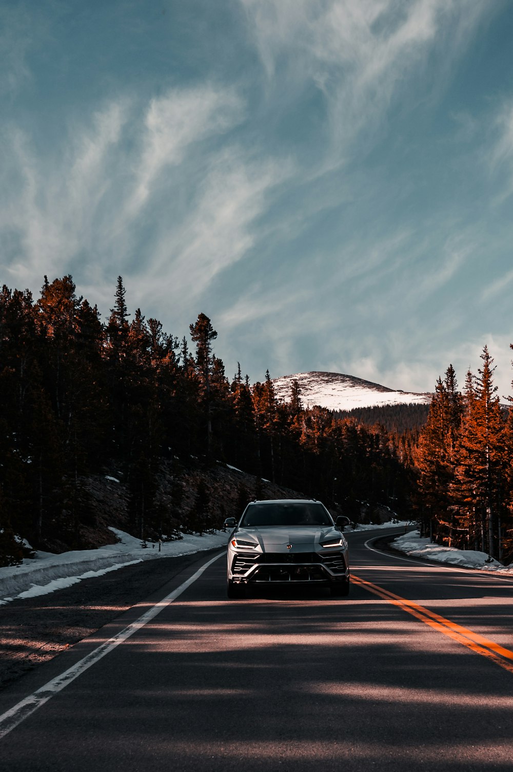 a car driving down a road with a mountain in the background